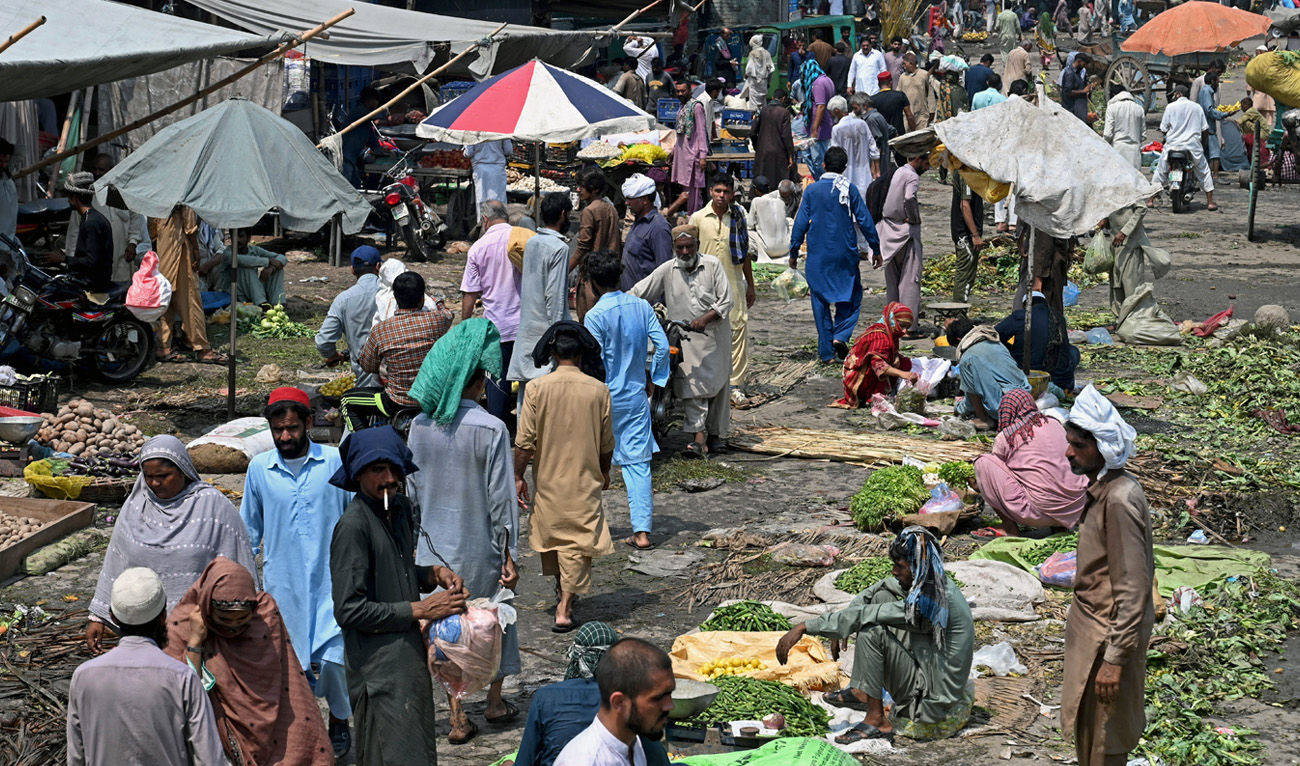 People buy vegetables at a local market in Lahore on August 30, 2022. (AFP)