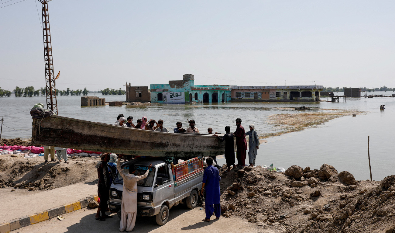 People launch a wooden boat into rising flood waters on the Indus highway, following rains and floods during the monsoon season in Mehar, Pakistan, on August 31, 2022. (REUTERS)