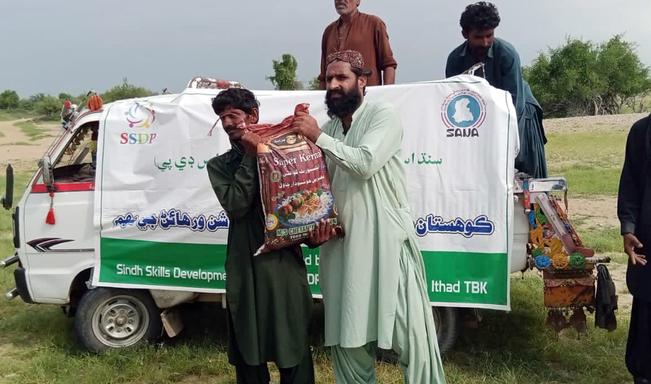 A team of volunteers from Dr. Mansour Memon's Sindh Skills Development Program organisation distributes ration bags among flood affected people in Dadu, Pakistan on August 23, 2022. (Supplied)