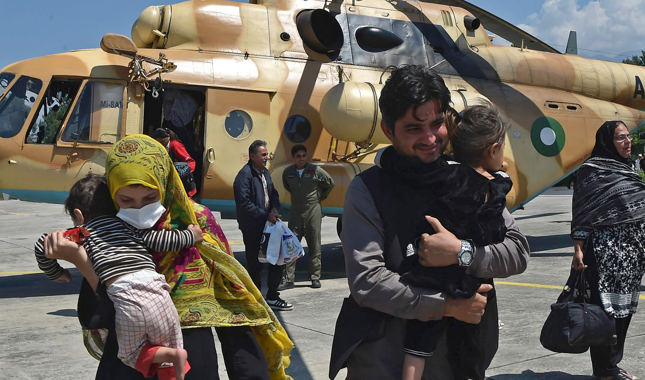 Stranded local tourists disembark from a Pakistan's army helicopter after they were rescued by army from the flood-hit tourist areas in Saidu Sharif, the capital of Swat valley in the Khyber Pakhtunkhwa province on August 30, 2022. (AFP)