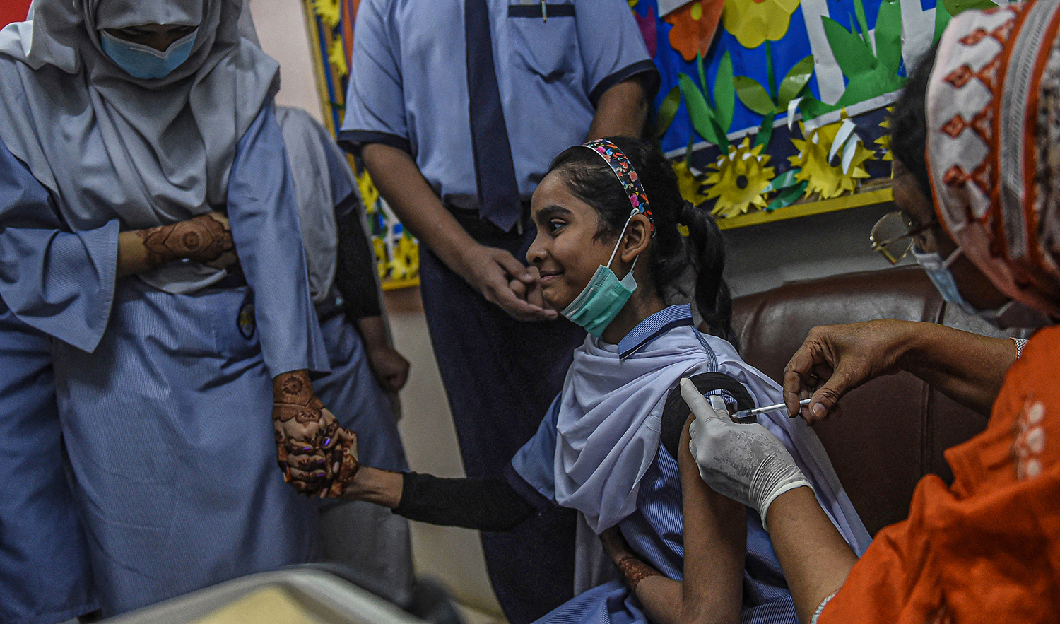 A health worker inoculates a student with a dose of the Pfizer vaccine against the Covid-19 coronavirus at a school in Karachi, Pakistan, on February 14, 2022. (AFP/File)