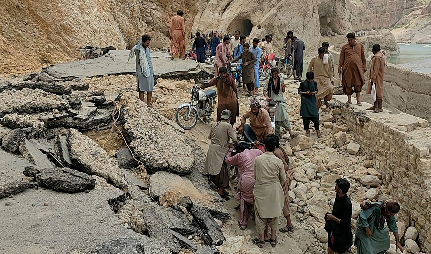In this picture taken on September 2, 2022 internally displaced flood affected people take a road damaged by flood waters as they try to reach a safer place in Bolan district of Pakistan's Balochistan province. (AFP)