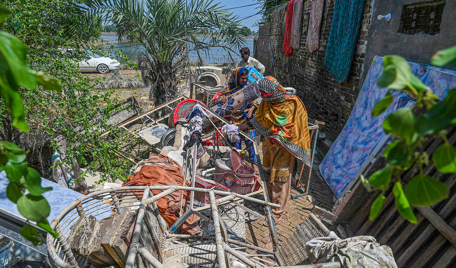 Mureed Hussain helps other family members to dry the dowry belongings of his daughter Nousheen, which were damaged by flood waters at his house in Fazilpur, Pakistan, on September 3, 2022. (AFP)