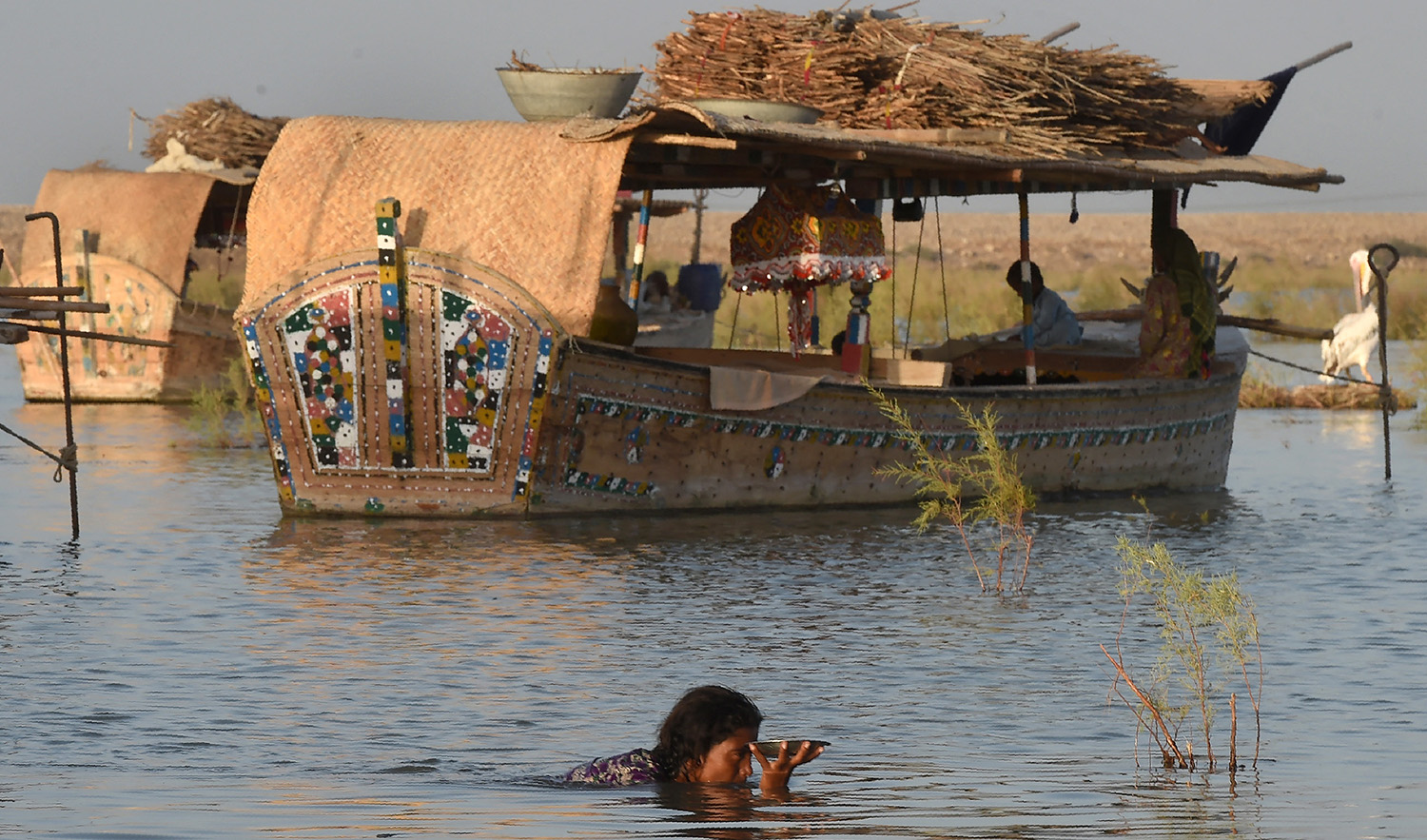 A woman holds up a plate of food as she makes her way through the water in front of the floating boathouses on Manchar lake on September 9, 2016. (AFP/File)