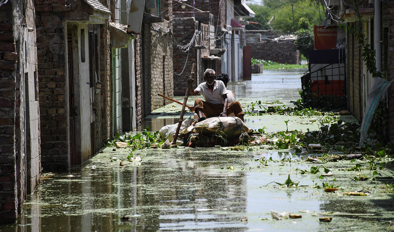 Men use a makeshift raft as they cross a flooded street in a residential area, following rains during the monsoon season in Hyderabad, Pakistan on September 5, 2022. (REUTERS)