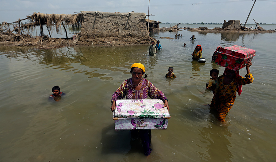 Women carry belongings salvaged from their flooded home after monsoon rains, in the Qambar Shahdadkot district of Sindh Province, of Pakistan, Sept. 6, 2022. (AP)