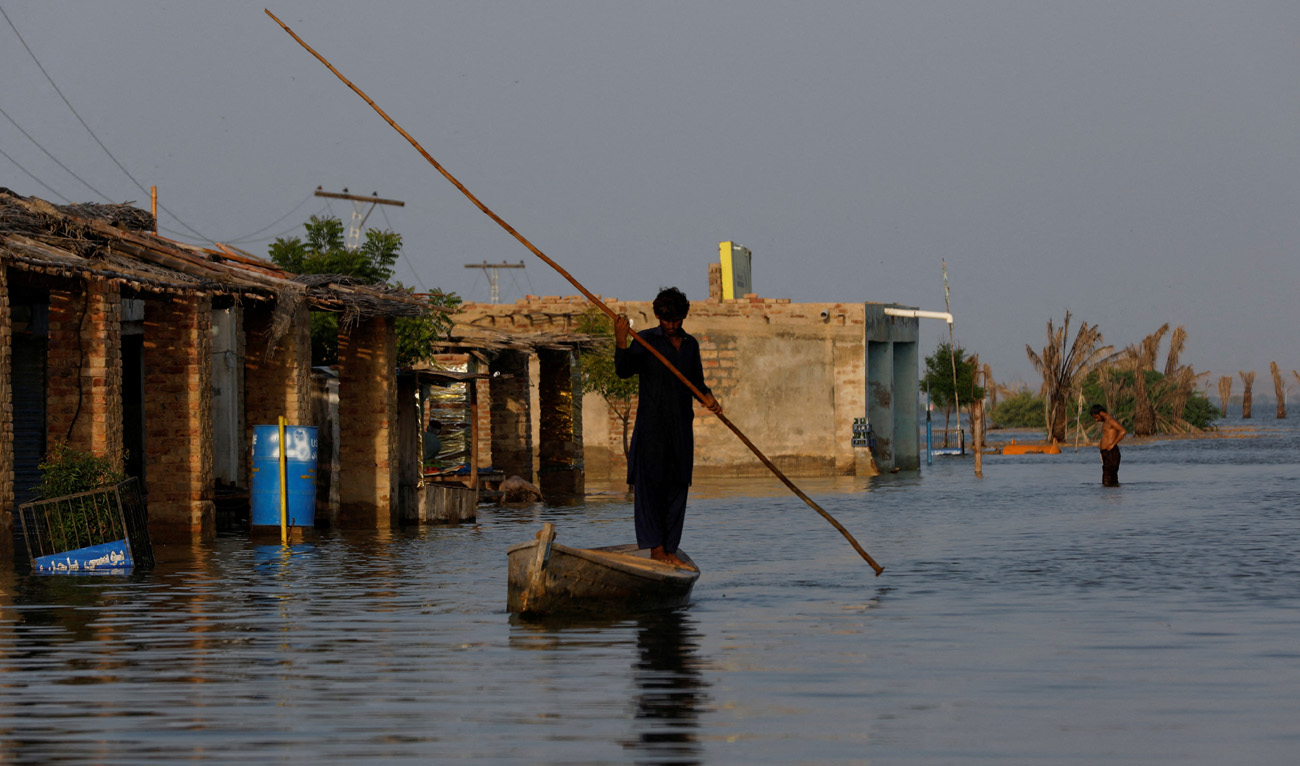 A man rows his boat as he passes through flooded market, following rains and floods during the monsoon season in Bajara village, at the banks of Manchar lake, in Sehwan, Pakistan September 6, 2022. (REUTERS)