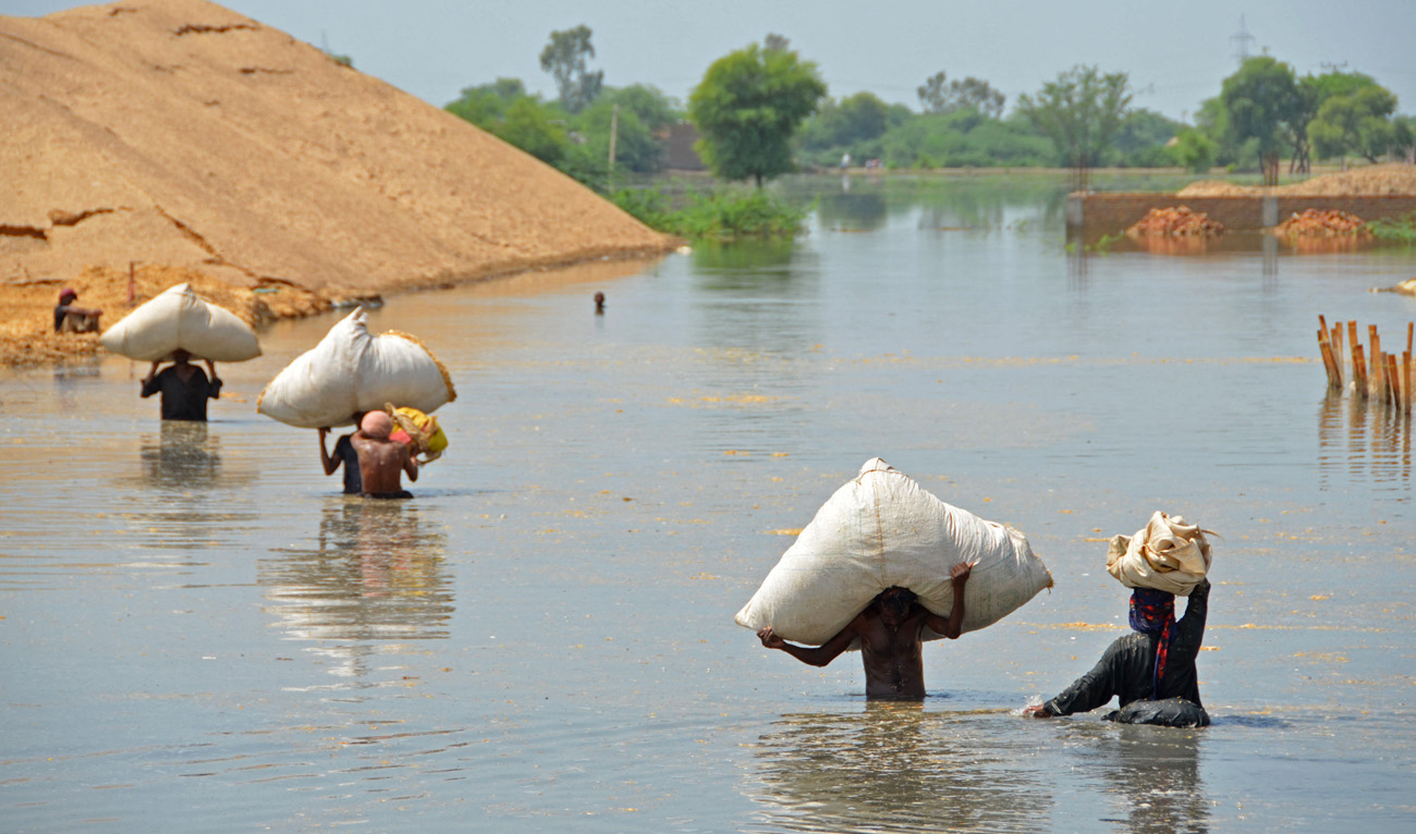 Internally displaced flood-affected people shift husk for their animals in a flood-hit area following heavy rains in Dera Allah Yar town of Jaffarabad district in Balochistan province on September 7, 2022. (AFP)