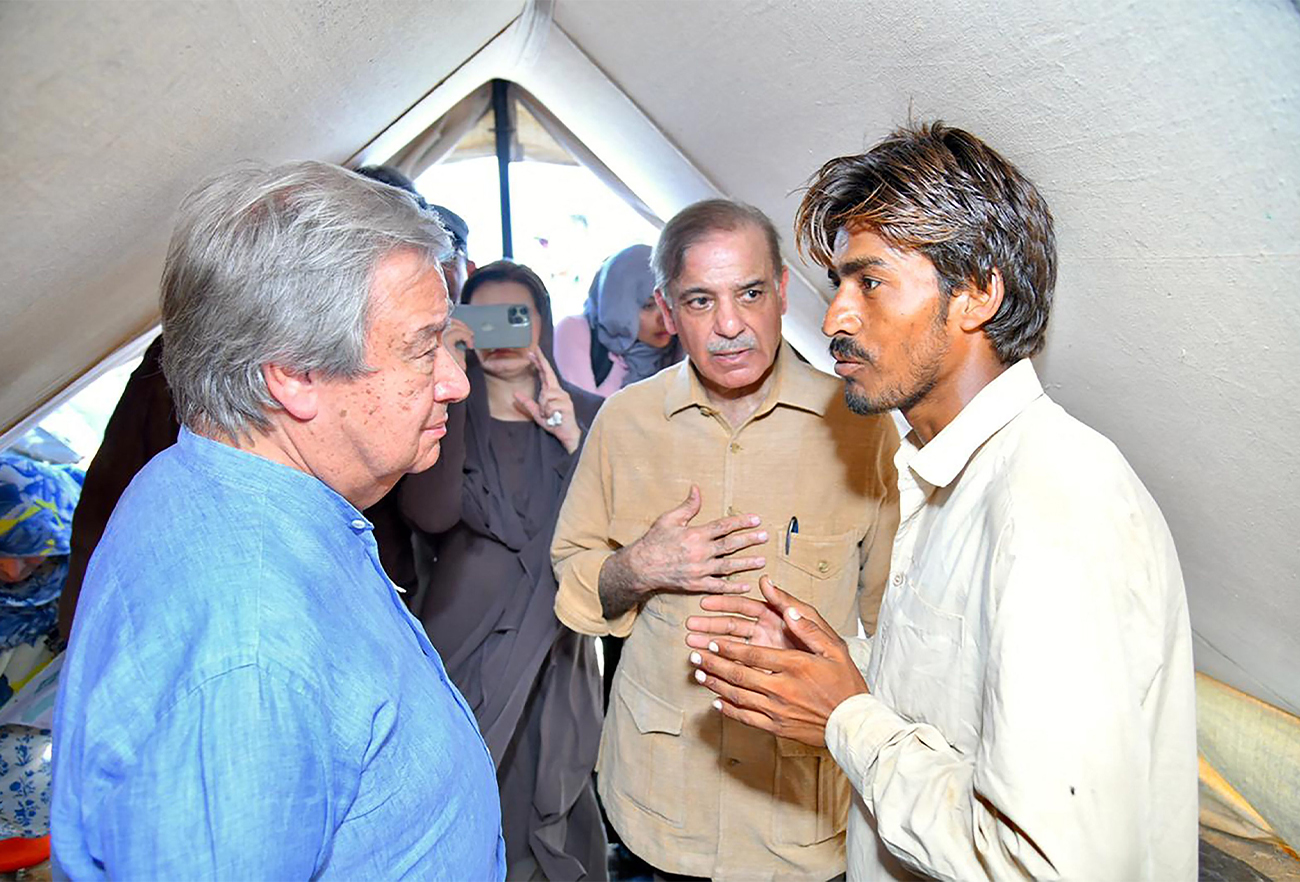 This handout picture released by Pakistan Prime Minister's Office on September 10, 2022, shows Pakistan's PM Shehbaz Sharif (C) and UN Secretary-General Antonio Guterres (L) meeting internally displaced people at a makeshift camp during their visit to flood-affected Usta Muhammad city in Jaffarabad district in Balochistan province. (AFP)