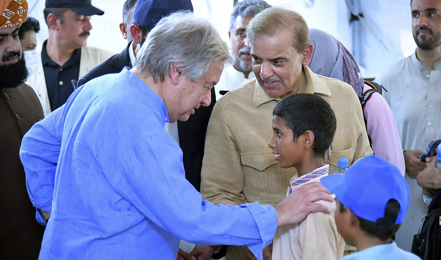 Prime Minister Shahbaz Sharif, center right, and U.N. Secretary-General Antonio Guterres, left, interact with children at a school set up at a flood relief camp in Jaffarabad, Pakistan, on September 10, 2022. (Photo courtesy: Pak PMO)