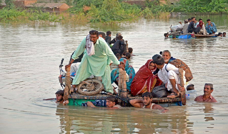 Internally displaced people wade through floodwaters after heavy monsoon rains in Jaffarabad district in Balochistan province on September 8, 2022. (AFP)