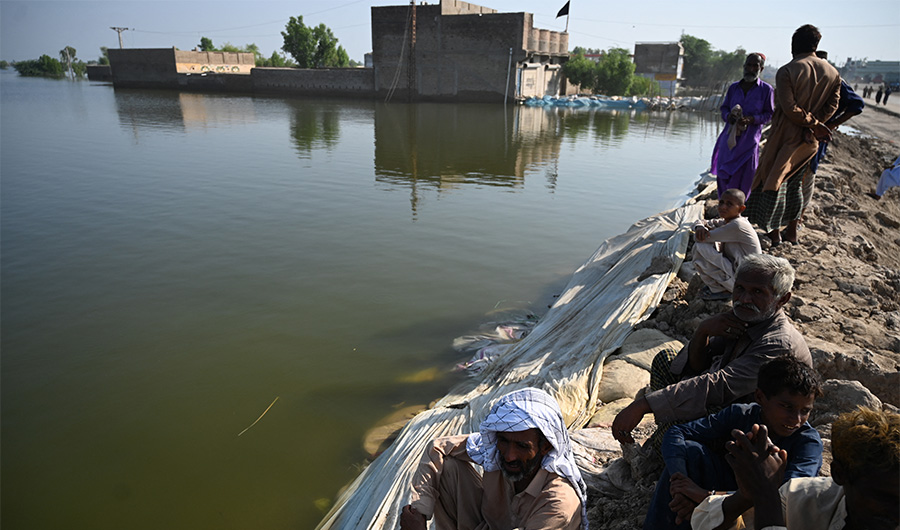Flood-affected people gather by an embankment in Mehar city after heavy monsoon rains in Dadu district, Sindh province on September 9, 2022. (AFP)