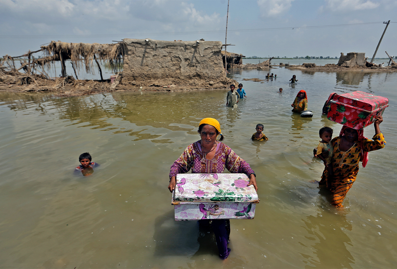 Women carry belongings salvaged from their flooded home after monsoon rains, in the Qambar Shahdadkot district of Sindh Province, of Pakistan, on September 6, 2022. (AP)