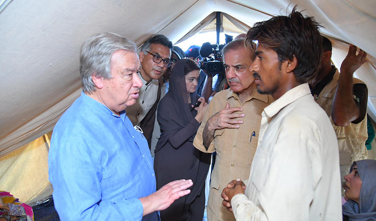 Primer Minister Shehbaz Sharif (C) and United Nations Secretary-General Antonio Guterres (L) meeting internally displaced people at a makeshift camp in flood-affected Usta Muhammad city in Balochistan province on September 10, 2022. (Prime Minister's Office)