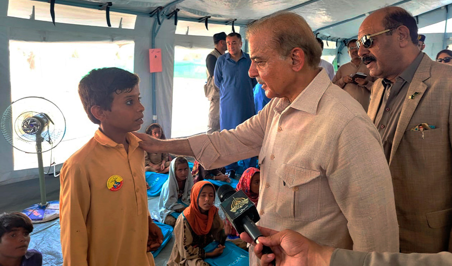 In this handout photo released by Press Information Department, Prime Minister Shahbaz Sharif, second right, talks to a student at a makeshift school inside a tent in the flood-hit area of Suhbatpur in Baluchistan, Pakistan. (AP)