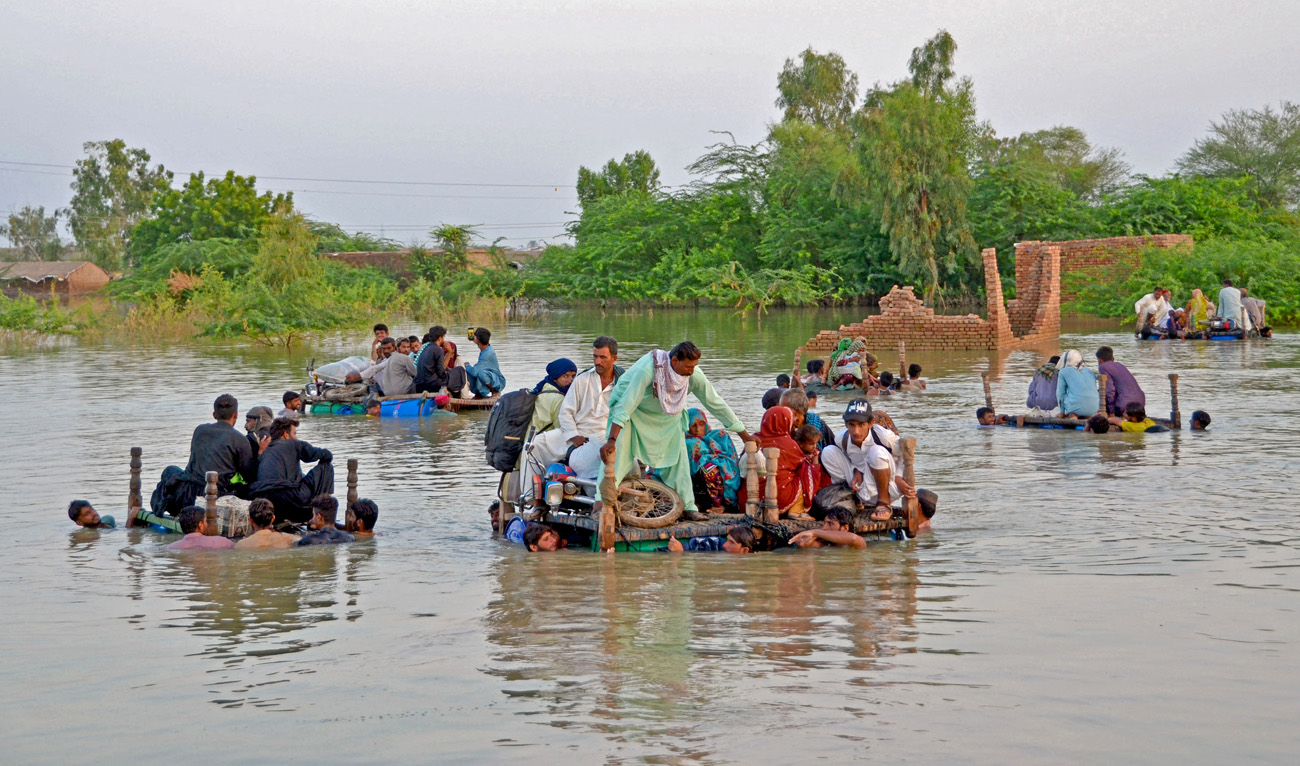 Internally displaced people wade through floodwaters after heavy monsoon rains in Jaffarabad district in Balochistan province on September 8, 2022. (AFP)