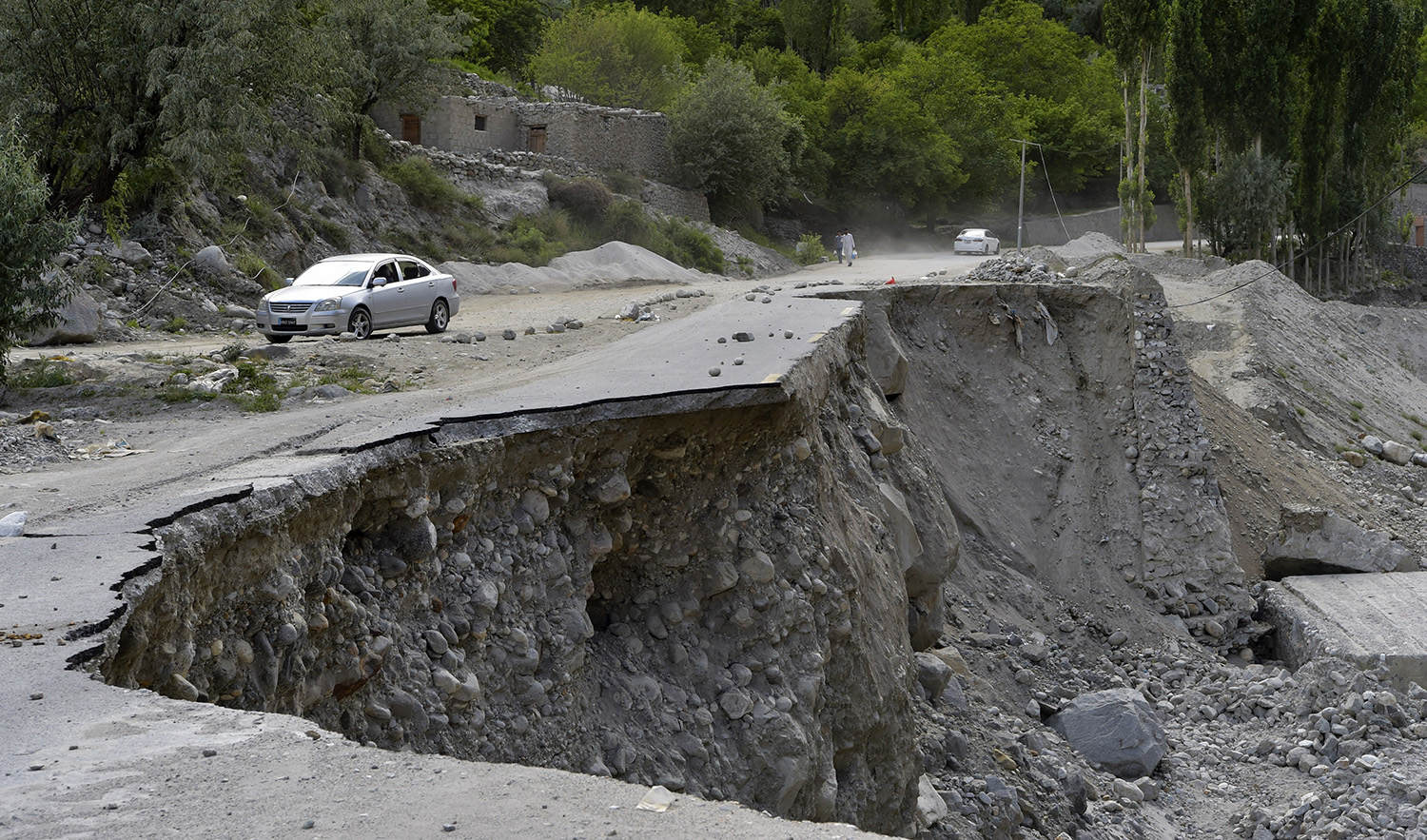 A vehicle drives past a partially collapsed section of the Karakoram Highway damaged after a lake outburst because of a melting glacier, near Hassanabad village of Pakistan's Gilgit-Baltistan region on June 9, 2022. (AFP/File)