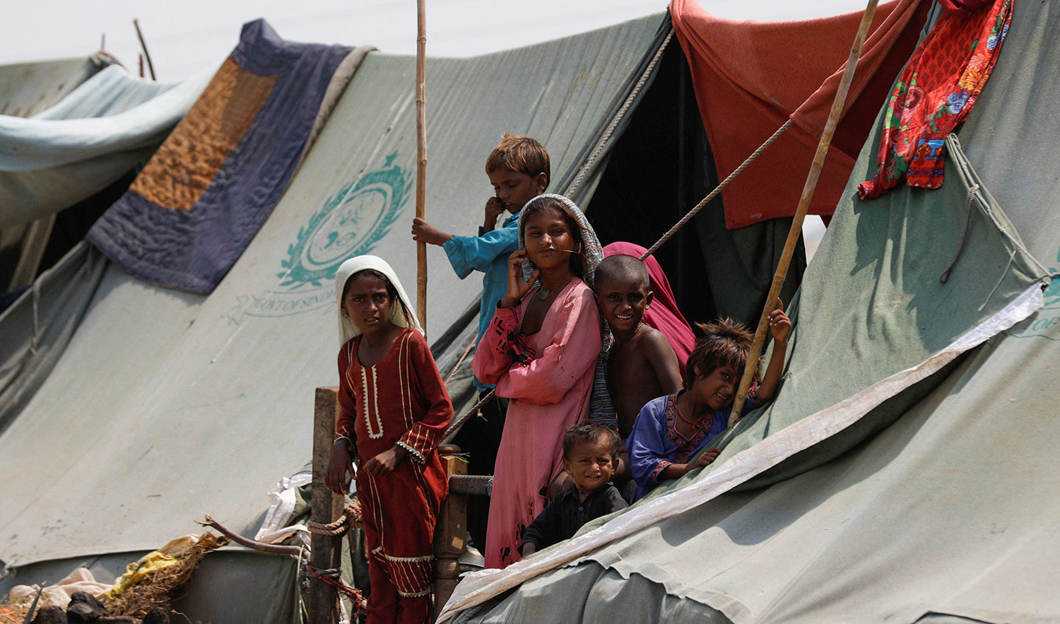 Children, who became displaced, stand outside their family tent while waiting for food handouts and relief material, following rains and floods during the monsoon season in Sehwan, Pakistan on September 14, 2022. (REUTERS)