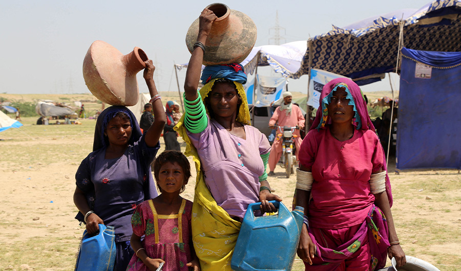 Internally displaced women carry pots to fill drinking water in a flood-hit area following heavy monsoon rains at Maqbaro village in Hyderabad, Sindh province on September 9, 2022. (AFP)