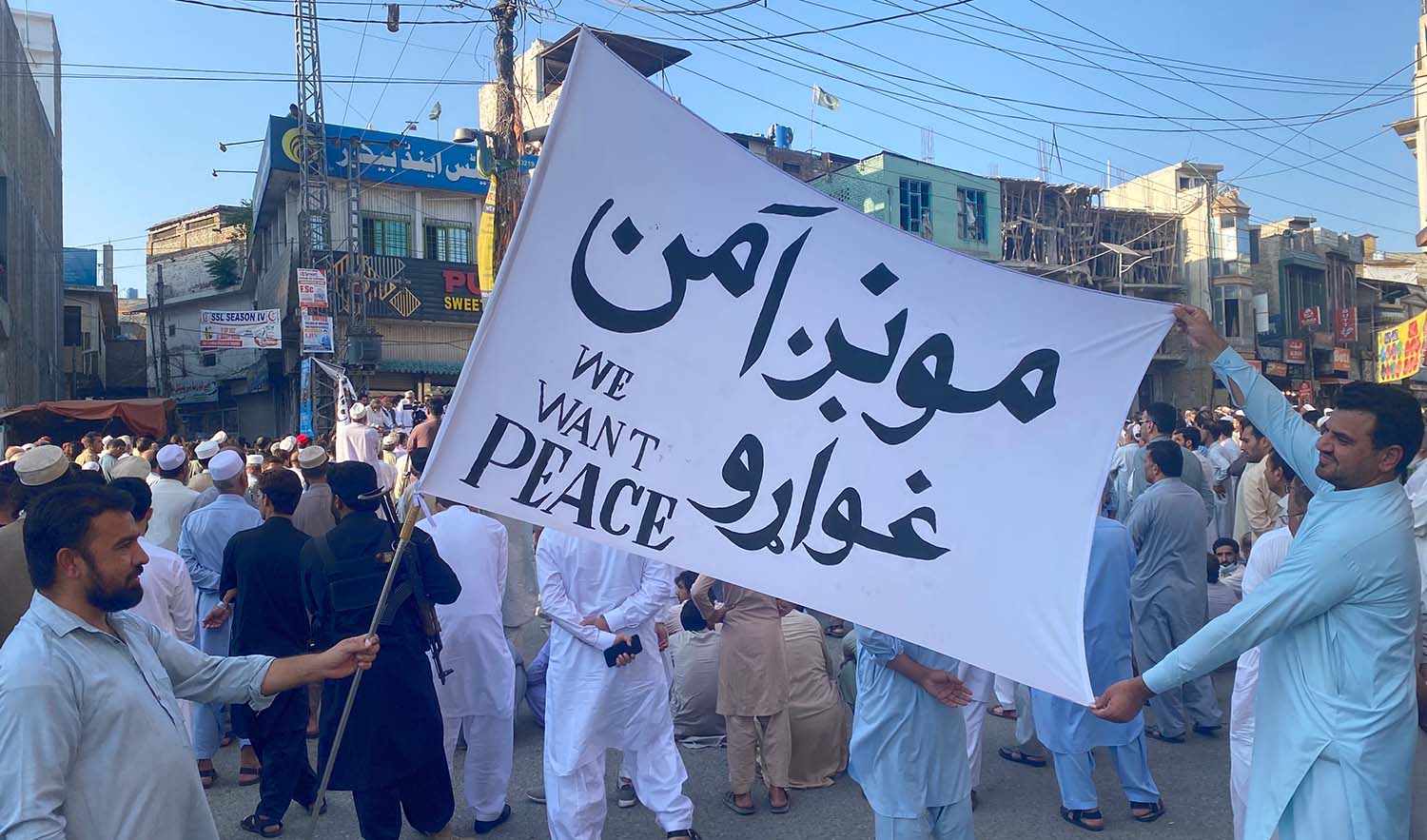 Men hold up flag that reads "We want peace" as hundreds take to the streets in Mingora on Sunday to protest against the possible return of the Pakistani Taliban to Swat. (AN photo by Naimat Khan)