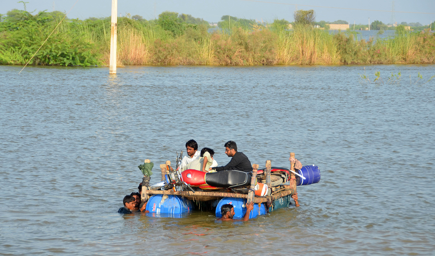 Internally displaced people wade through floodwaters after heavy monsoon rains at Usta Mohammad city in Jaffarabad district of Pakistan's Balochistan province on September 18, 2022. (AFP)