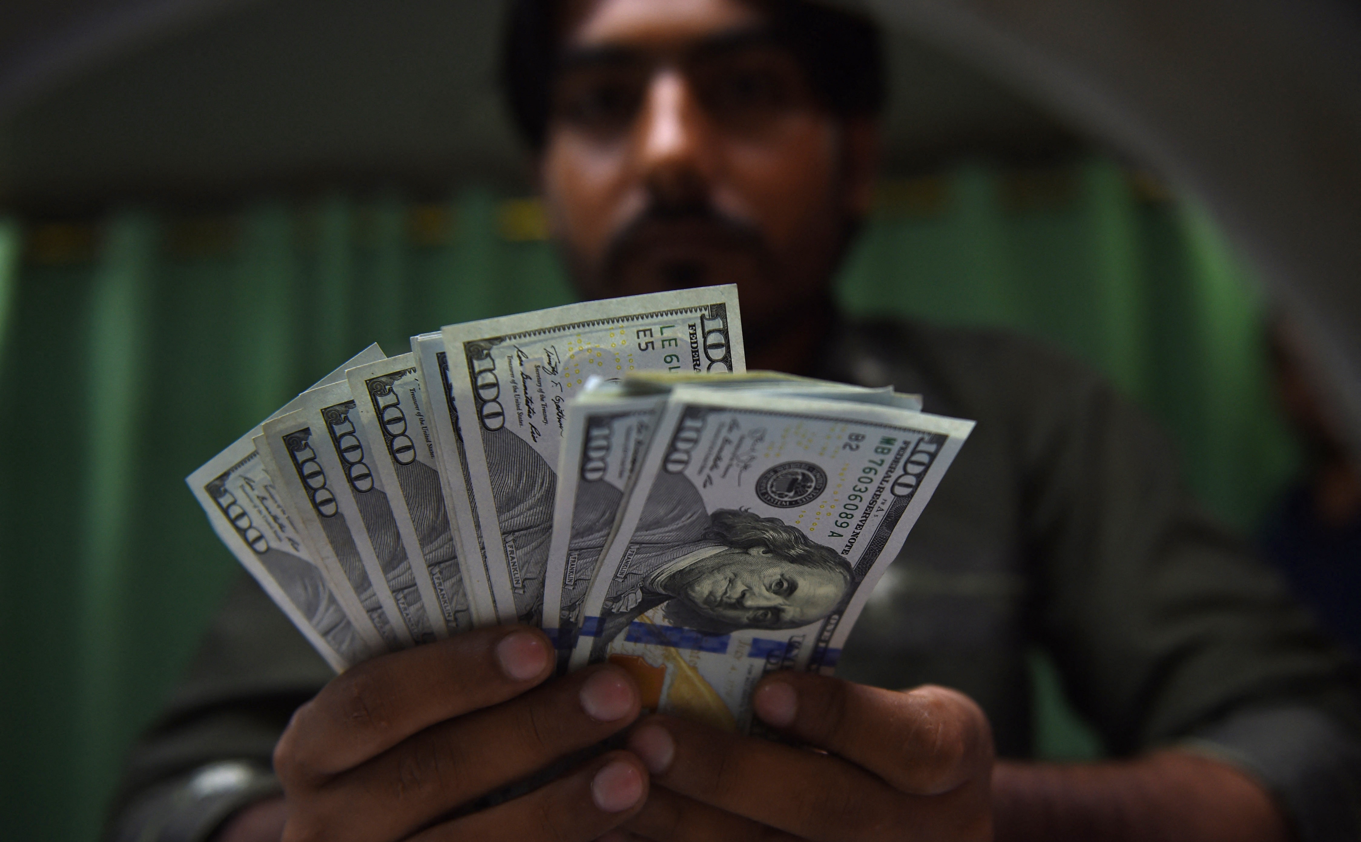 This photo taken on July 17, 2018 shows a Pakistani currency dealer counting US dollars banknotes at a currency exchange shop in Karachi. (AFP/File)