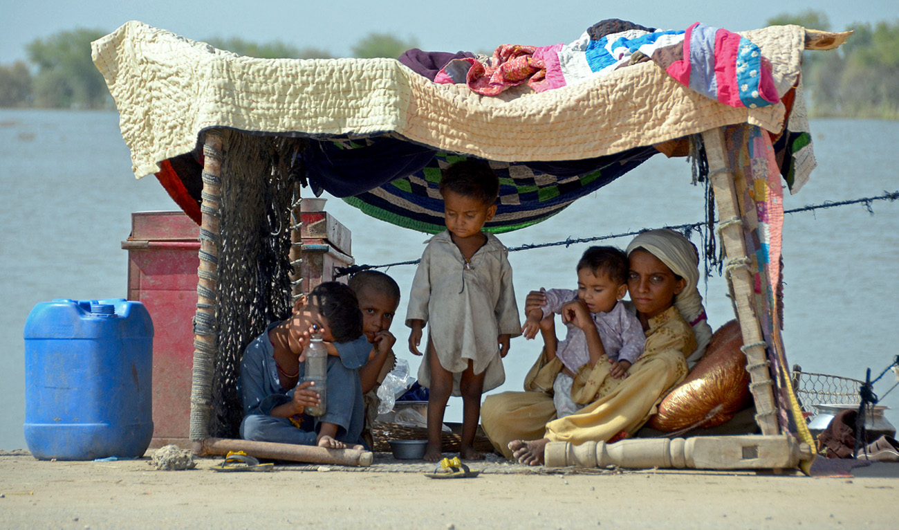 A flood-affected woman sits along with her children inside a temporary tent in a makeshift camp at Sohbatpur in Jaffarabad district of Balochistan province on September 19, 2022. (AFP)
