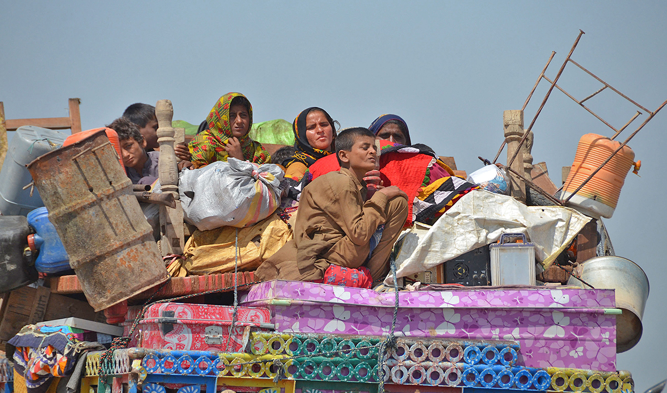 Displaced flood-affected families travel atop a tractor with their belongings near a makeshift camp at Dera Allah Yar in Jaffarabad district of Balochistan province on September 20, 2022. (AFP)