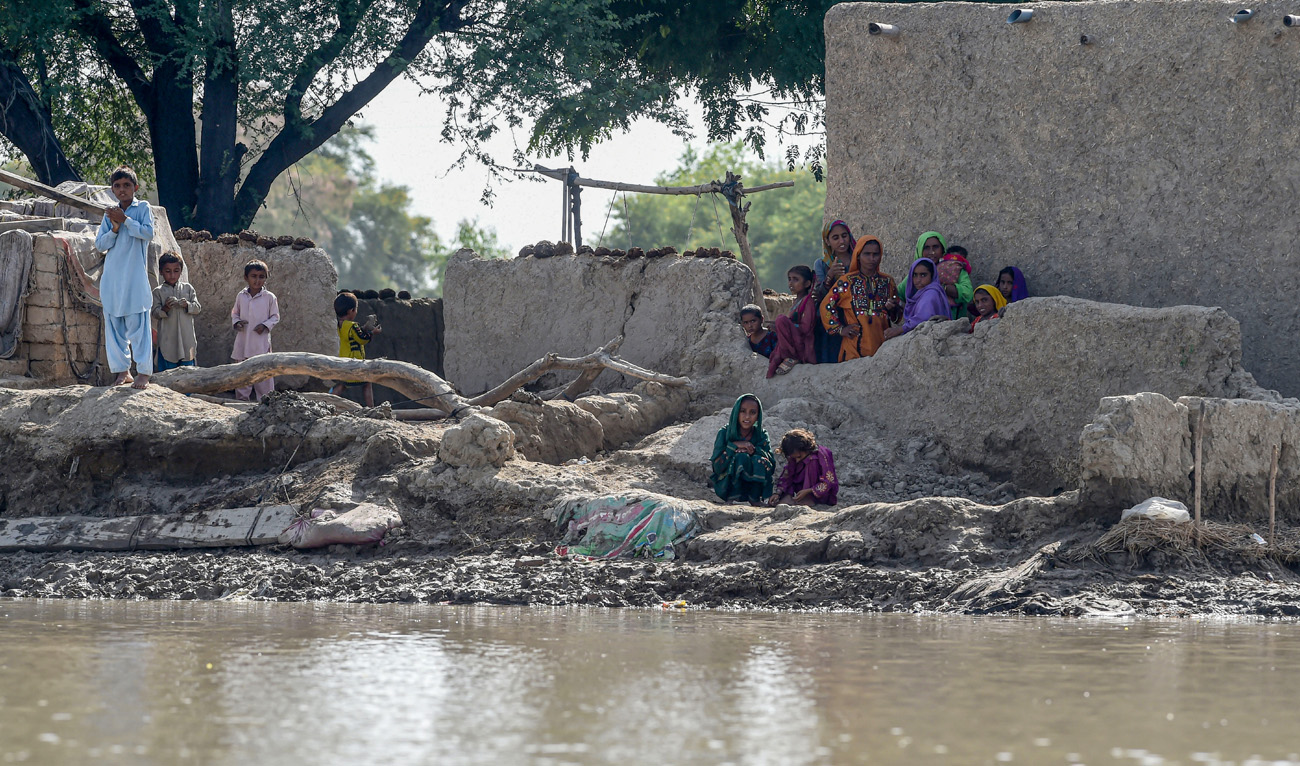 Flood affected people gather near their houses as they wait for relief aid in a flooded area following heavy monsoon rains in Rajanpur district of Punjab province on September 4, 2022. (AFP)