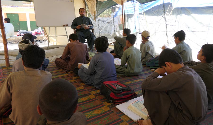 A teacher takes primary class inside a tent at Government Boys High School, Hanna Urrak in Balochistan, Pakistan on September 24, 2022. (AN Photo)