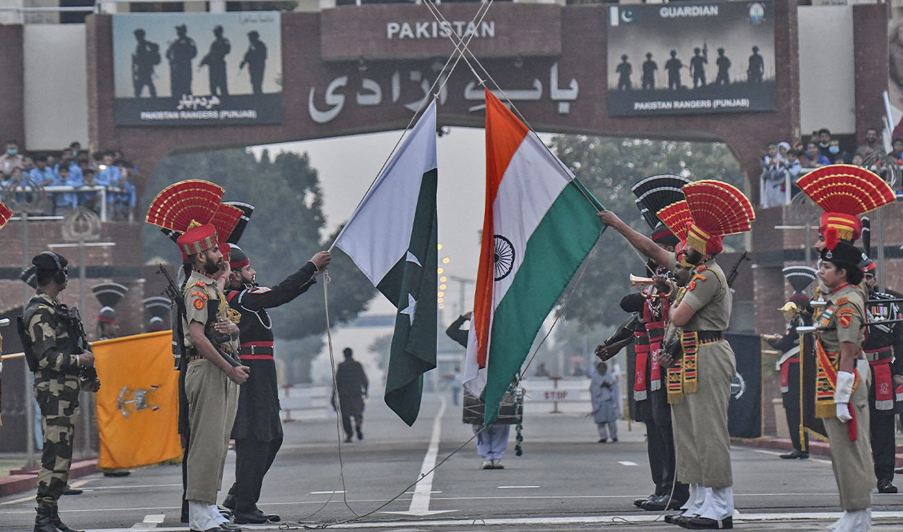 Indian Border Security Force (BSF) personnel and Pakistani Rangers (in black) lower their respective flags during the daily beating of the retreat ceremony at the India-Pakistan Wagah Border Post, about 35 km from Amritsar on November 15, 2021. (AFP/File)