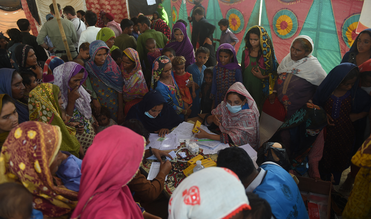 Local residents displaced by floods gather at a makeshift medical camp set in Dadu district, Sindh province on September 27, 2022. (AFP)