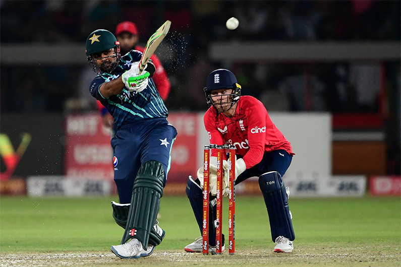 Pakistan's captain Babar Azam (L) plays a shot as England's wicketkeeper Phil Salt watches during the fourth Twenty20 international cricket match between Pakistan and England at the National Cricket Stadium in Karachi on September 25, 2022. (AFP)