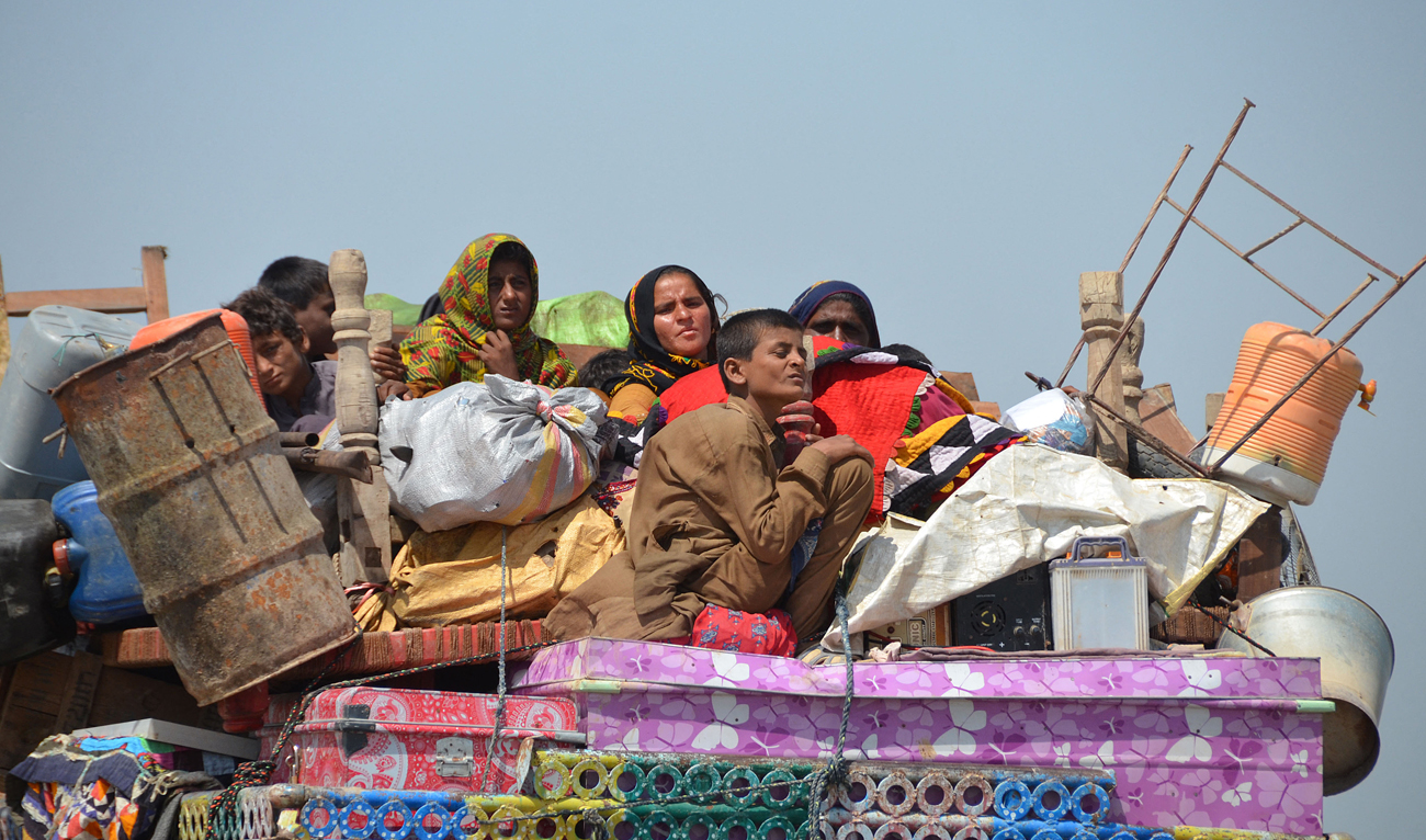 Displaced flood-affected families travel atop a tractor with their belongings near a makeshift camp at Dera Allah Yar in Jaffarabad district of Balochistan province on September 20, 2022. (AFP)