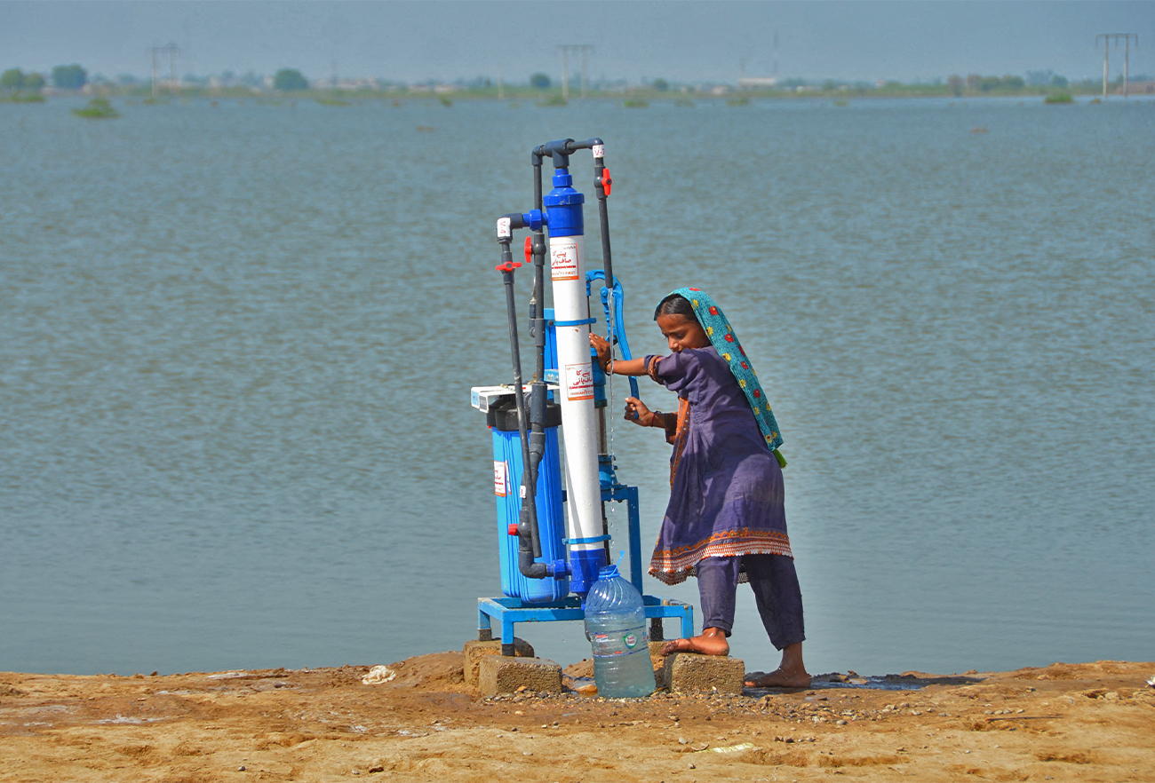 A flood-affected girl collect water from a filter pump in Dera Allah Yar town of Jaffarabad district in Balochistan province on September 17, 2022. (AFP)