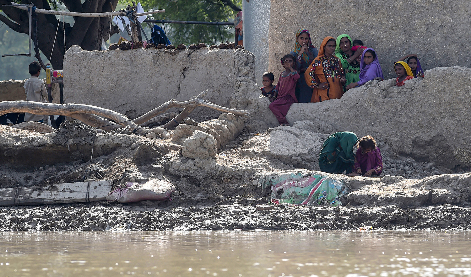 Flood affected people gather near their houses as they wait for relief aid in a flooded area following heavy monsoon rains in Rajanpur district of Pakistan's Punjab province on September 4, 2022. (AFP)