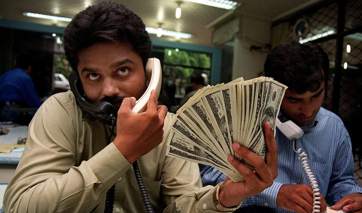 Pakistani money dealers busy on telephones amid a spurt in demand for the green back in the port city of Karachi, 27 May 2000. (AFP/File)