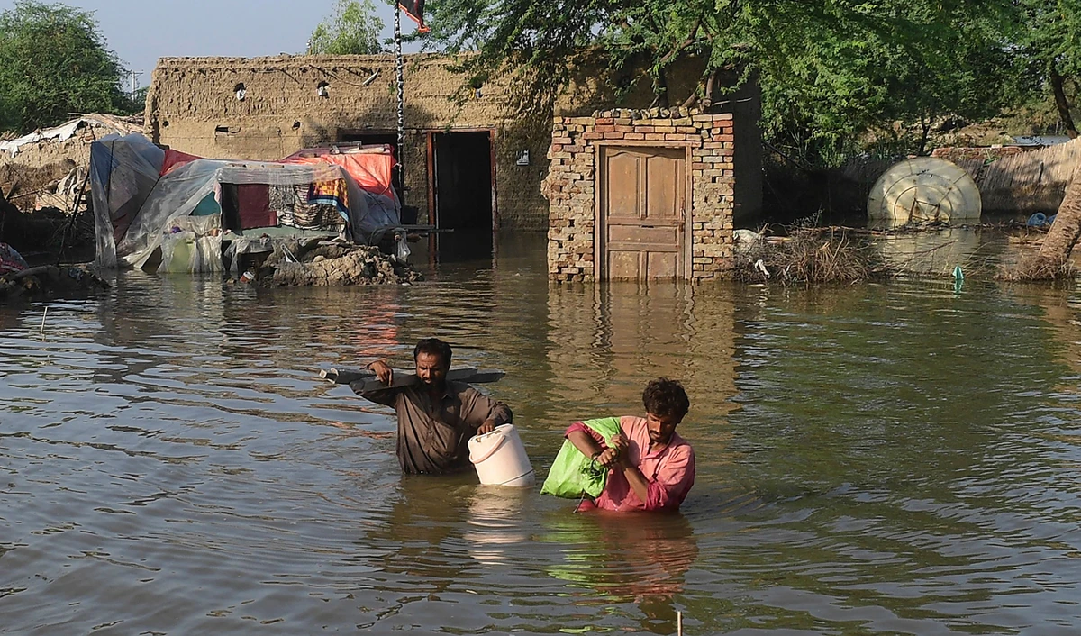 Flood affected people carry belongings out from their flooded home in Shikarpur, Sindh province, on August 31, 2022. (AFP)