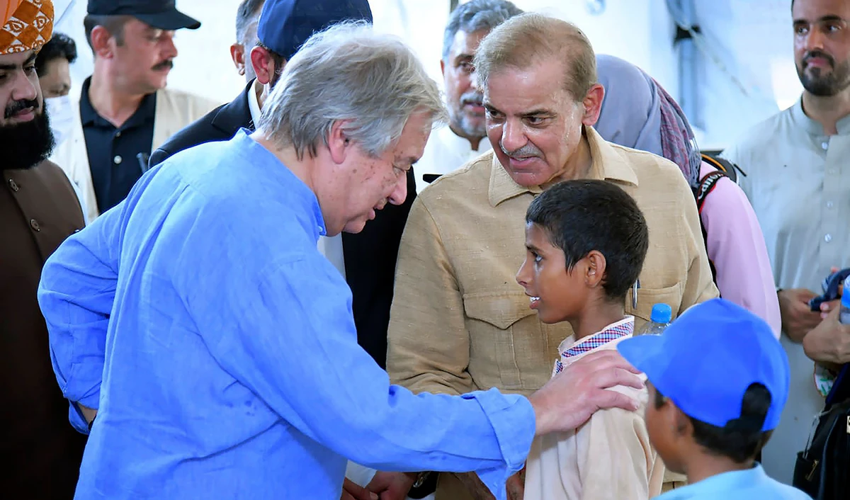 Prime Minister Shahbaz Sharif, center right, and U.N. Secretary-General Antonio Guterres, left, interact with children at a school set up at a flood relief camp in Jaffarabad, Pakistan, on September 10, 2022. (Photo courtesy: Pak PMO)