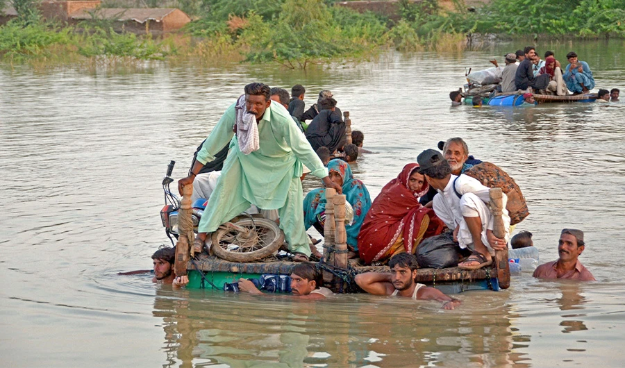 Internally displaced people wade through floodwaters after heavy monsoon rains in Jaffarabad district in Balochistan province on September 8, 2022. (AFP)