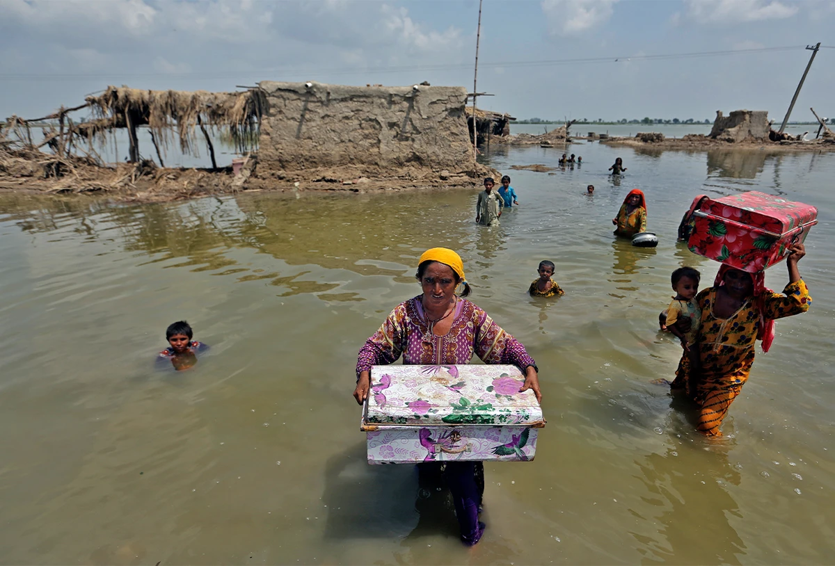 Women carry belongings salvaged from their flooded home after monsoon rains, in the Qambar Shahdadkot district of Sindh Province, of Pakistan, on September 6, 2022. (AP)