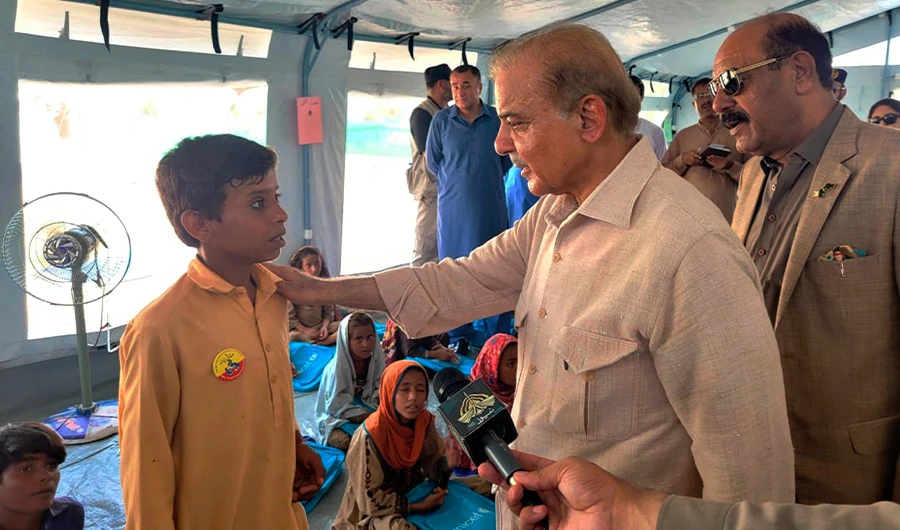 In this handout photo released by Press Information Department, Prime Minister Shahbaz Sharif, second right, talks to a student at a makeshift school inside a tent in the flood-hit area of Suhbatpur in Baluchistan, Pakistan. (AP)
