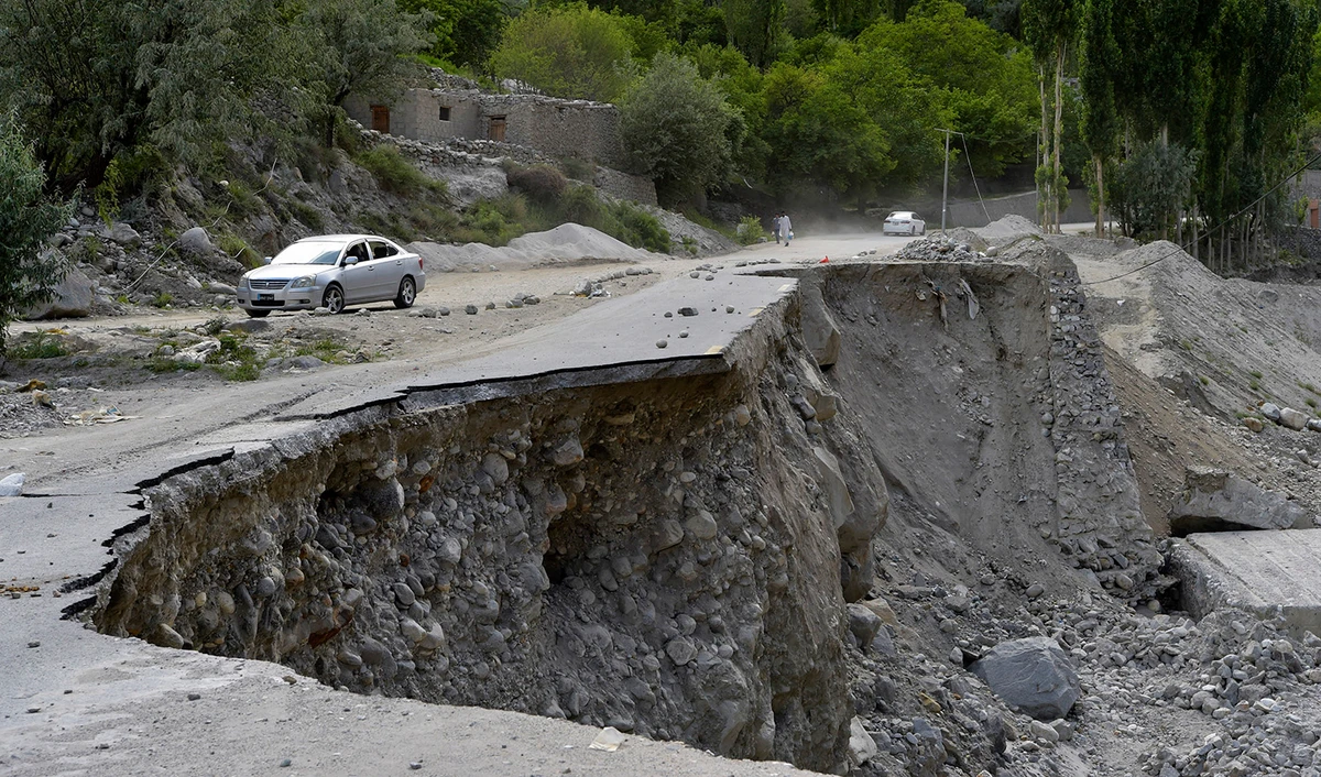 A vehicle drives past a partially collapsed section of the Karakoram Highway damaged after a lake outburst because of a melting glacier, near Hassanabad village of Pakistan's Gilgit-Baltistan region on June 9, 2022. (AFP/File)