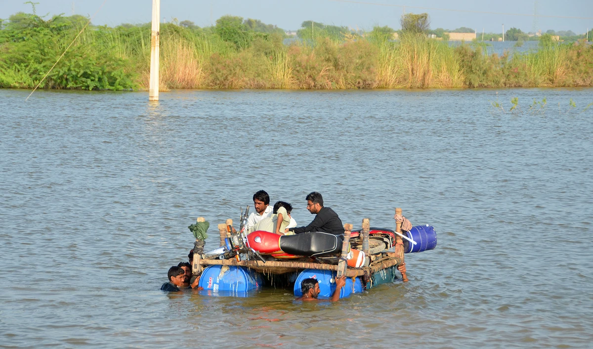 Internally displaced people wade through floodwaters after heavy monsoon rains at Usta Mohammad city in Jaffarabad district of Pakistan's Balochistan province on September 18, 2022. (AFP)