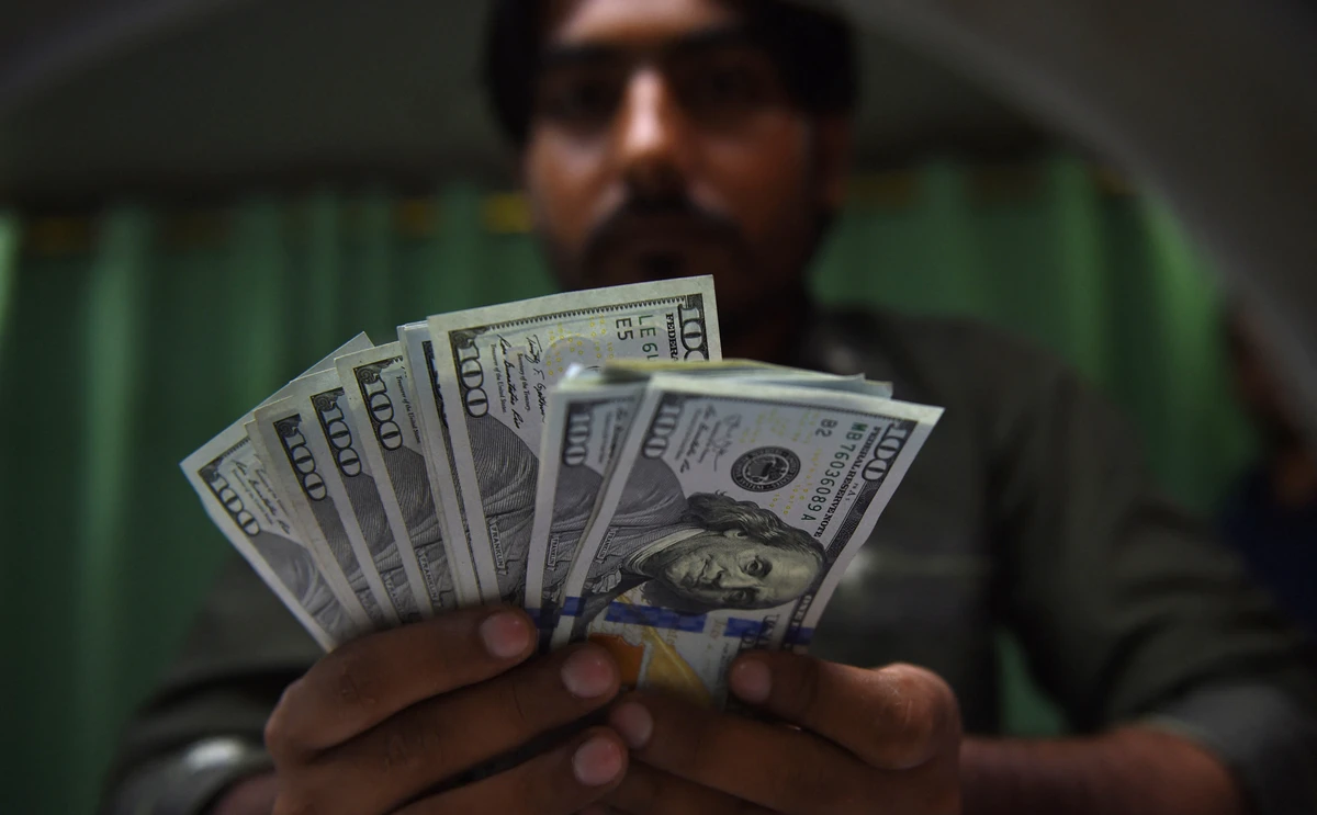 This photo taken on July 17, 2018 shows a Pakistani currency dealer counting US dollars banknotes at a currency exchange shop in Karachi. (AFP/File)
