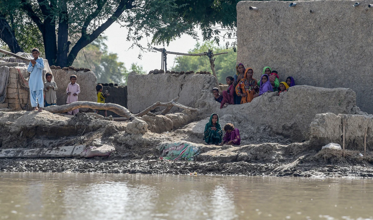 Flood affected people gather near their houses as they wait for relief aid in a flooded area following heavy monsoon rains in Rajanpur district of Punjab province on September 4, 2022. (AFP)