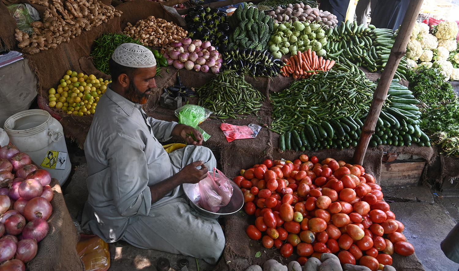 A vendor weighs vegetables for a customer at a local market in Lahore on August 29, 2022, amid a big hike in prices of food items in the wake of massive floods in Pakistan. (AFP/File)