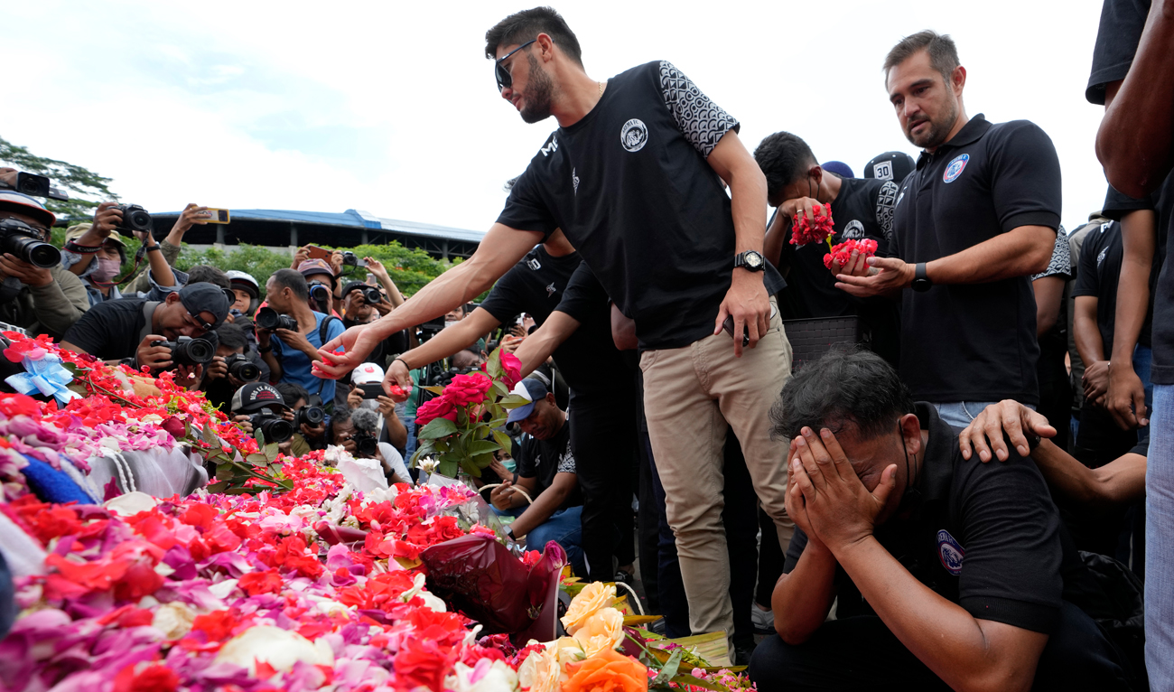 Players and officials of the soccer club Arema FC pray outside Kanjuruhan Stadium where riots broke out on Saturday night, in Malang, Indonesia, October 3, 2022. (AP)