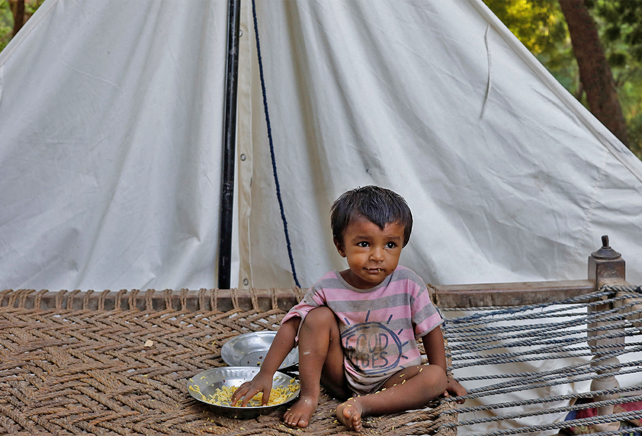 A boy, who's family displaced because of the floods, eats boiled rice while sitting outside his family tent while taking refuge in a camp, in Sehwan, Pakistan, on September 30, 2022. (REUTERS)