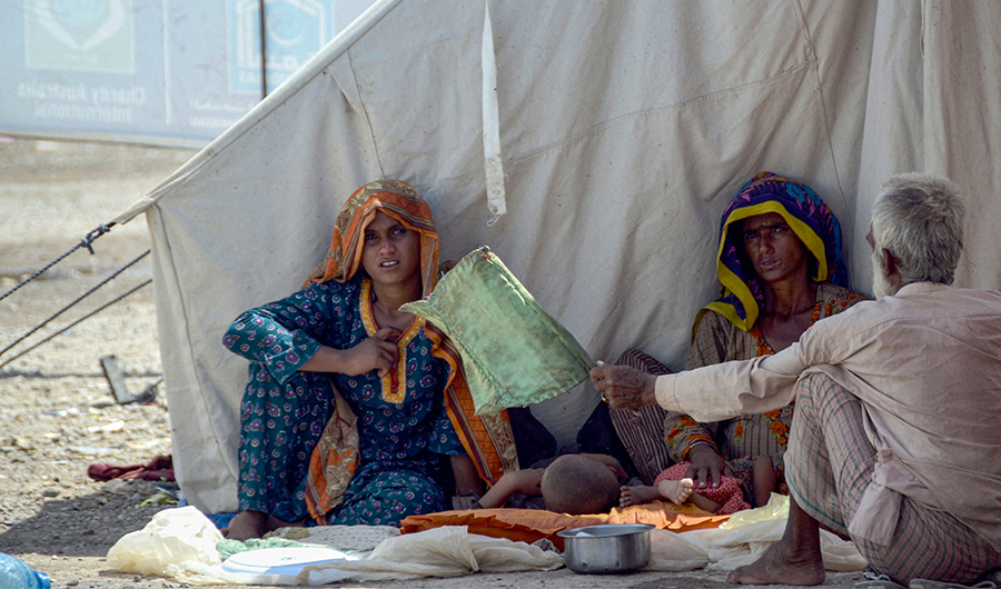 Internally displaced flood-affected people sit next to their tent as they take refuge at a makeshift camp at Dera Allah Yar in Jaffarabad district of Balochistan province on September 22, 2022. (AFP)